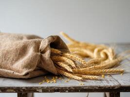 Golden Wheat Stalks Overflowing from a Burlap Sack on Weathered Wooden Table. photo