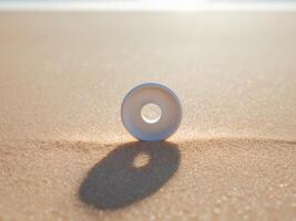 White Ceramic Donut Object Resting on a Sand Surface with a Shallow Depth of Field. photo