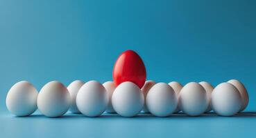 A red egg is standing out from a group of white eggs photo