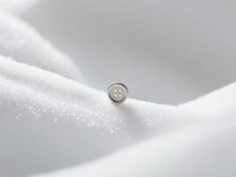 A button is sitting on top of a white cloth photo