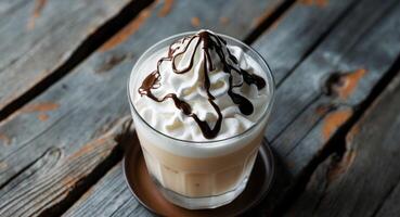 Creamy coffee drink with chocolate syrup on the wooden table, closeup shot. photo