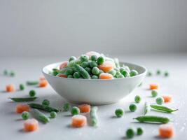 A bowl of peas and carrots on a white table photo