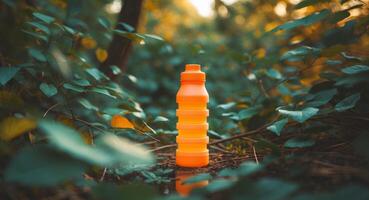 An orange water bottle sits in the middle of a forest photo