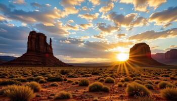 large rock formations rise from a sandy plain, casting long shadows as the sun sets. photo