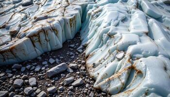 the edge of a glacier meets rocky earth, ice and stone in stark contrast. photo