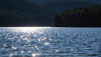 sunlight dances on the surface of a lake surrounded by dark green forest. photo