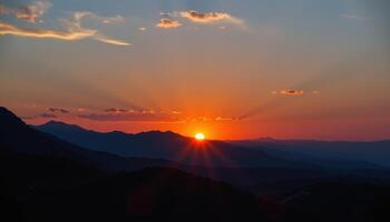 the sky turns brilliant orange as the sun sets behind a line of rocky peaks. photo