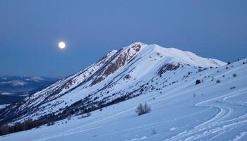 a snow covered ridge glows under the pale light of a full moon. photo
