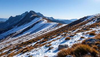 a rocky mountain ridge covered in patches of snow and hardy alpine grass. photo