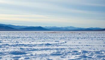 a frozen tundra plain under a pale blue sky, broken only by distant rolling hills. photo