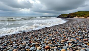 a windswept coastline of pebbles and grass under fast moving clouds. photo