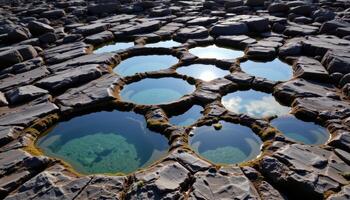 a cluster of tidal pools reflecting the sky among jagged coastal rocks. photo