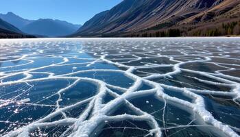 a mountain lake partially frozen, with ice crystals forming intricate patterns. photo