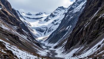 a narrow mountain pass carved by ice, now dotted with late spring snow. photo