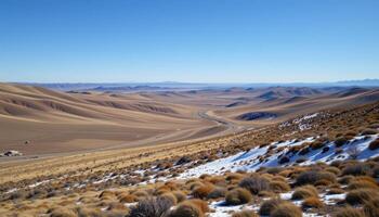 a remote tundra landscape with rolling hills and scattered patches of snow under a clear sky. photo