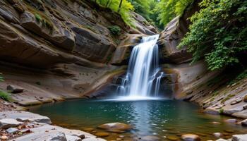 a hidden waterfall plunging through rock into a silent, forested pool. photo