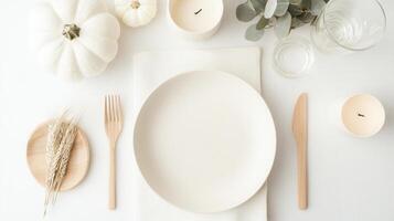 Thanksgiving table setting decorated with white pumpkins, wheat, candles and eucalyptus leaves a on white background seen from above photo