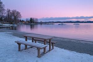 A bench and a table on a beach at sunset photo