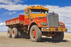 A large truck driving on a dirt road photo
