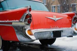 An old red car is parked on the street in the snow photo