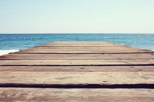 A wooden pier leads to the ocean photo