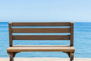 A wooden bench sitting on a concrete ledge overlooking the ocean photo
