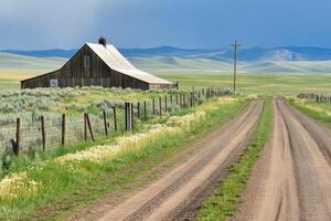 A dirt road leads to a barn and a fence photo