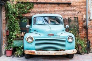 An old blue truck parked in front of a brick wall photo