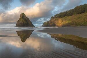 A rock formation is reflected in the water at sunset photo