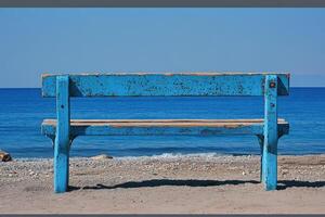 A blue bench sitting on a beach photo
