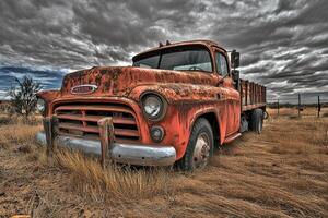 An old rusty truck is parked in a field photo