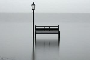 Solitary bench and lamppost submerged in calm, misty water photo
