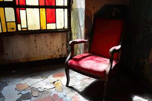 A red chair sitting in a room with stained glass windows photo