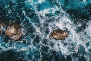 An aerial view of the ocean with rocks and waves photo