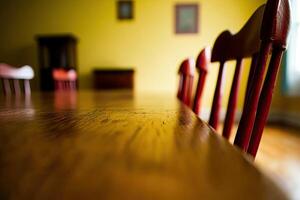 A wooden table with red chairs in front of a yellow wall photo