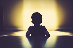 A silhouette of a child sitting at a table photo