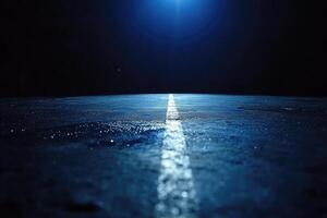 A dark road with a bright light shining in the distance photo