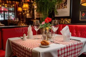 A table with red and white checkered table cloth and red chairs photo