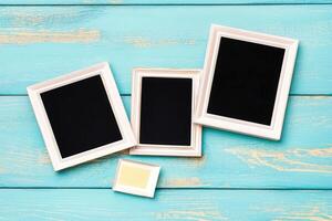 Three empty frames on a blue wooden table photo