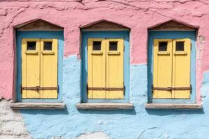 Three colorful windows on a pink and blue wall photo