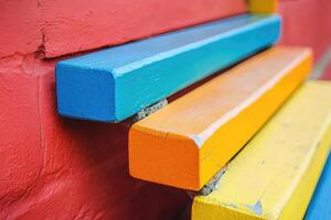 A colorful bench sitting against a red wall photo
