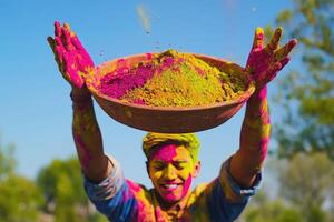 A man holding up a bowl of colorful powder photo
