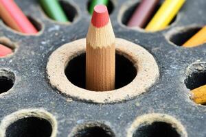 A pencil is sitting in a hole with many colored pencils photo