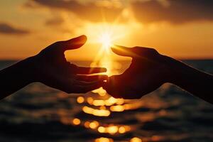 Two hands meet at sunset over the ocean photo
