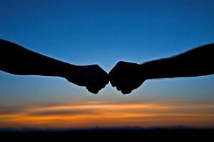 Two fists meeting at sunset photo