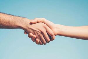 Two hands shaking against a clear blue sky. Friendly and collaborative photo