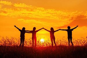 Silhouette of four friends, arms linked, at sunset photo