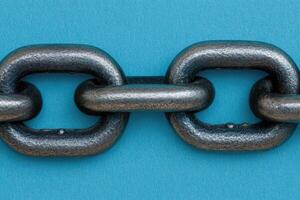 Close-up of a heavy-duty metal chain link against a vibrant blue backdrop. The links are robust and interlocking, showcasing industrial strength photo