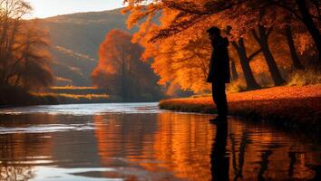 Man Contemplating by Autumn River with Golden Reflections at Sunset photo