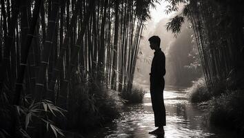 Person Standing in Stream Surrounded by Bamboo Forest in Grayscale photo